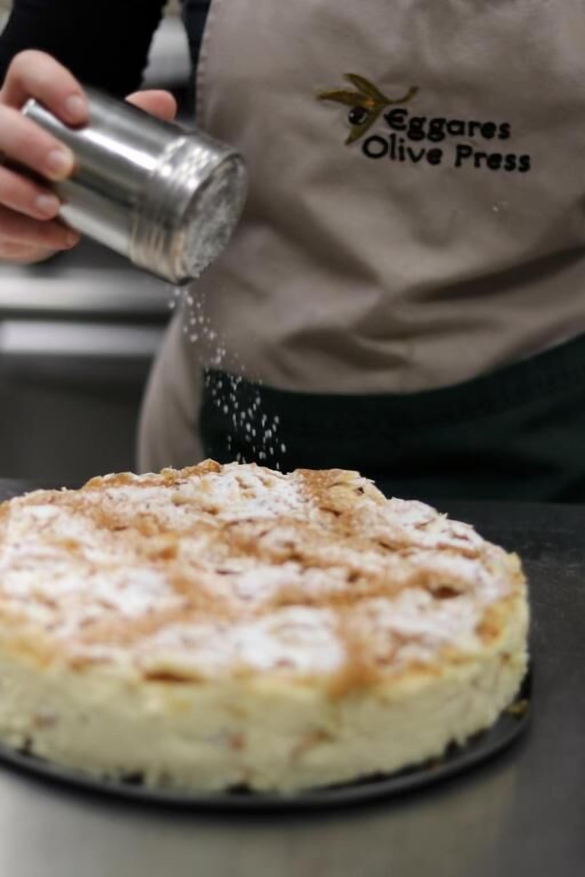 A person sprinkling a powdery substance over a round dish.
