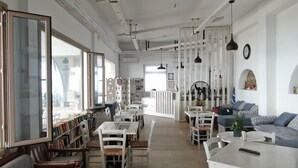 A spacious living area with a dining table, chairs, a sofa, and a bookshelf. - Artemis (Mykonos)