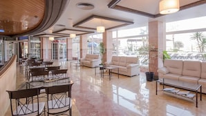 A spacious lobby with a curved ceiling, a seating area with sofas and chairs, and large windows offering views of the outside. - Blau Park (Sant Antoni de Portmany)