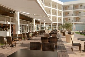 Un área de estar al aire libre con muebles de mimbre y una barra a la izquierda.