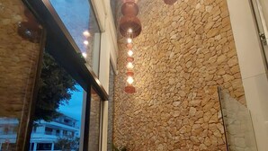 A modern interior with a stone wall, a seating area, and a view through a glass door. - Blau Park (Sant Antoni de Portmany)