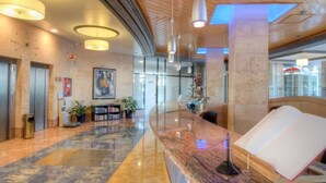 A spacious lobby with a marble reception desk, a large painting, and a modern ceiling design. - Blau Park (Sant Antoni de Portmany)
