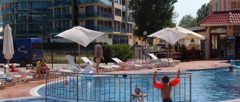 En säsongsöppen utomhuspool, parasoller och solstolar