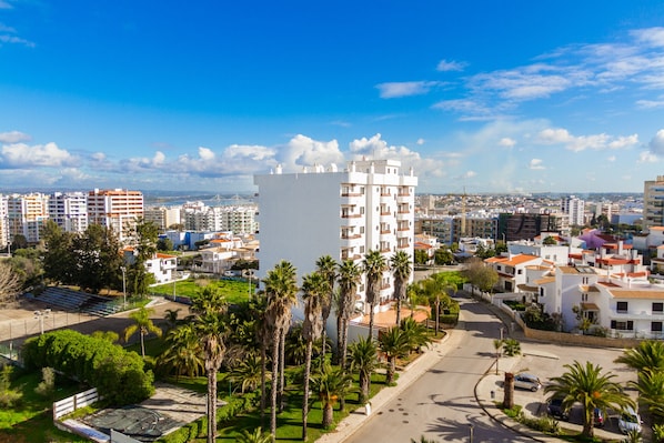 A residential area with a prominent white building, palm trees, and a clear blue sky. - Mirachoro Portimao (Portimão)