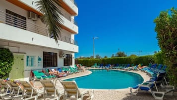 Una piscina al aire libre, sillones reclinables de piscina