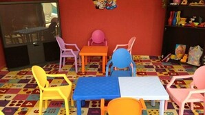 Une salle de jeux pour enfants avec des meubles aux couleurs vives et un sol à motifs.