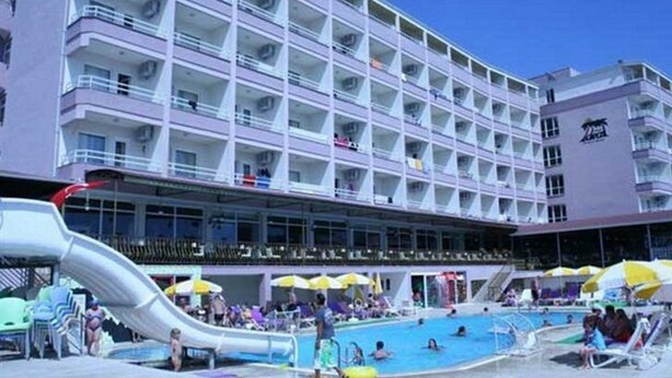 Un hôtel à plusieurs étages doté d’un espace piscine comprenant un toboggan et des parasols.