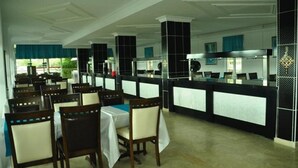 Un restaurant doté de nombreuses tables et chaises, d’un comptoir et offrant une vue sur l’extérieur.
