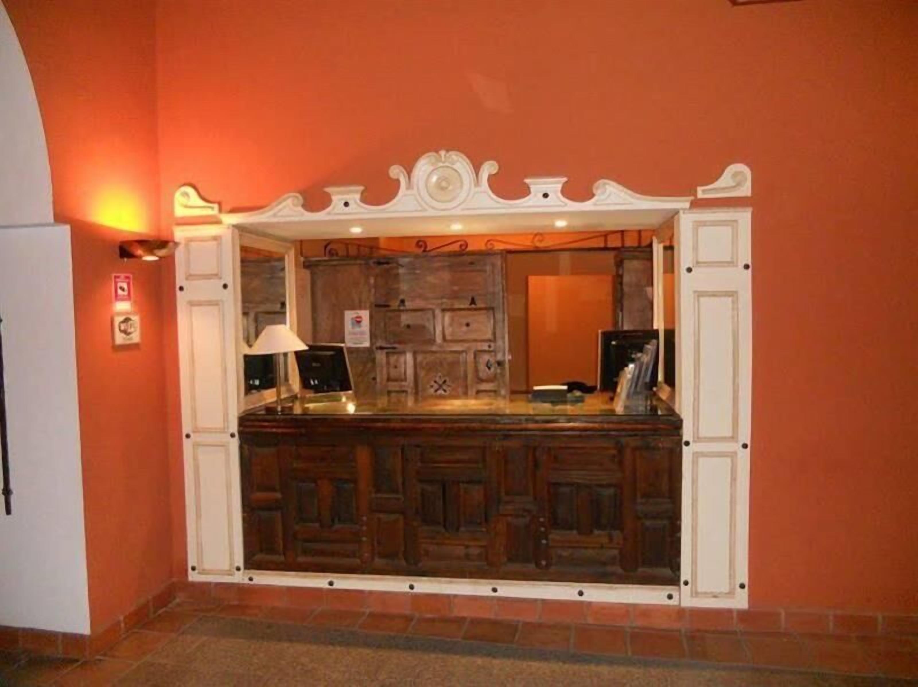 A reception area with a wooden counter, a white decorative arch, and a tiled floor.