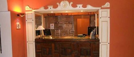 A reception area with a wooden counter, a white decorative arch, and a tiled floor.