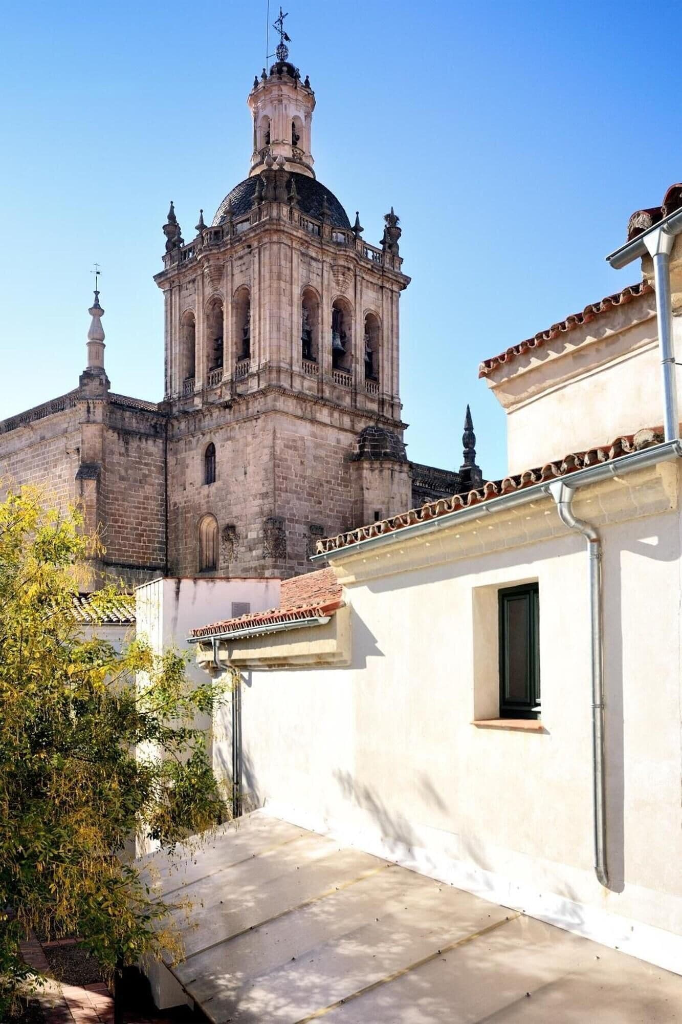 Une cour intérieure avec un bâtiment historique doté d’un clocher et de fenêtres en arc.