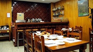 A restaurant with wooden walls, a bar area with bottles, and a poster of Andorra. - Valmar (Andorra la Vella)