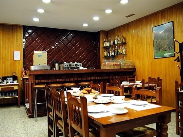 Un restaurante con paredes de madera, una zona de bar con botellas y un cartel de Andorra.