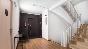 A modern interior with a wooden floor, a staircase with white railings, a black chair, and a small table. - Valmar (Andorra la Vella)