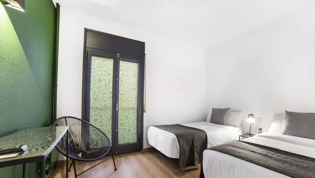 A room with two beds, a chair, a table, and a door with patterned glass. - Valmar (Andorra la Vella)