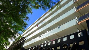 Un edificio de varios pisos con balcones y un cartel metálico grande con la palabra 