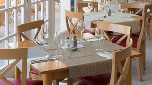 A restaurant with wooden tables and chairs, each set with cutlery and wine glasses. - Aparthotel Seth Isla Paraiso (Mercadal)