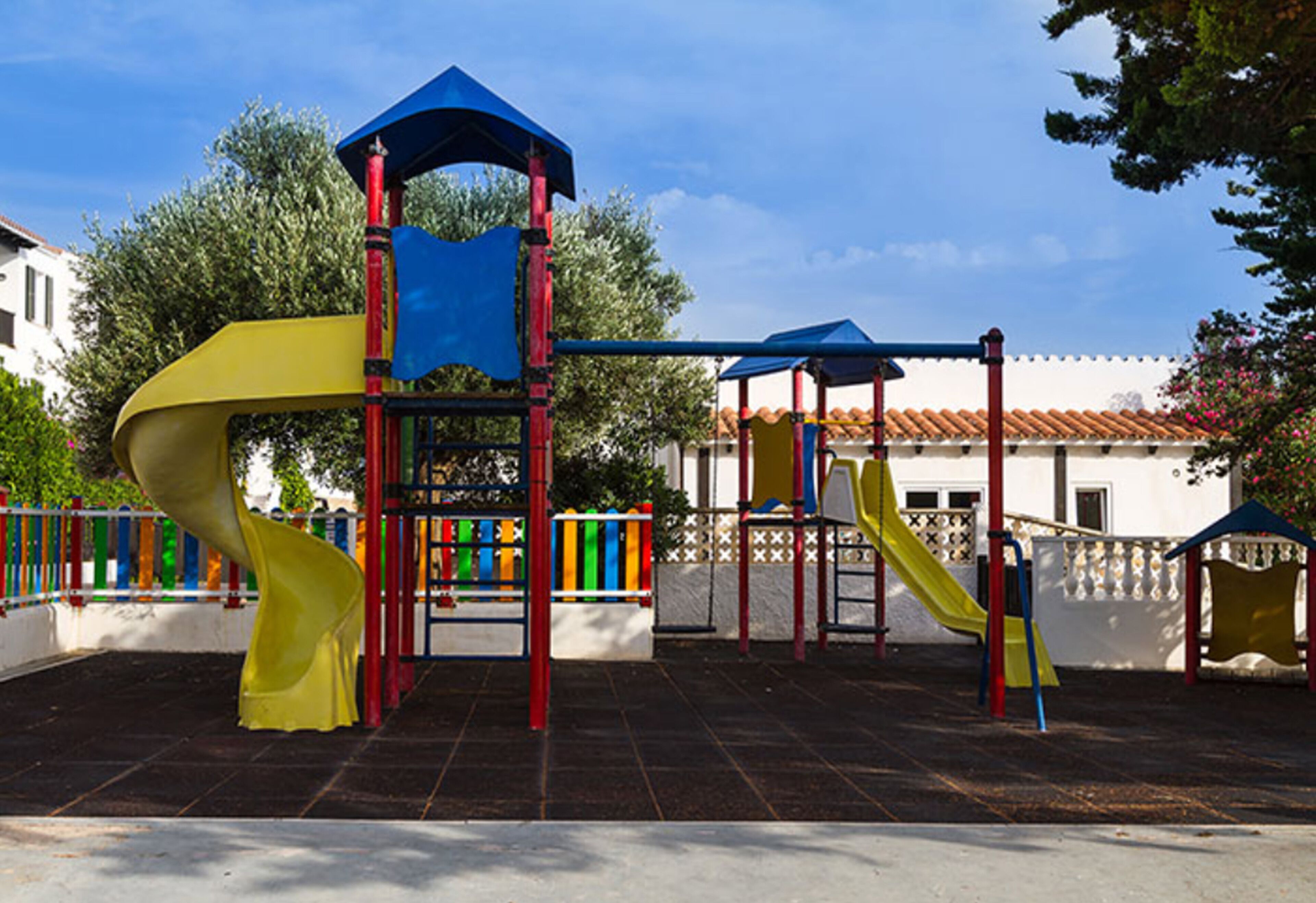 Un parque infantil con un tobogán amarillo, una red de escalada azul y un andamio rojo.