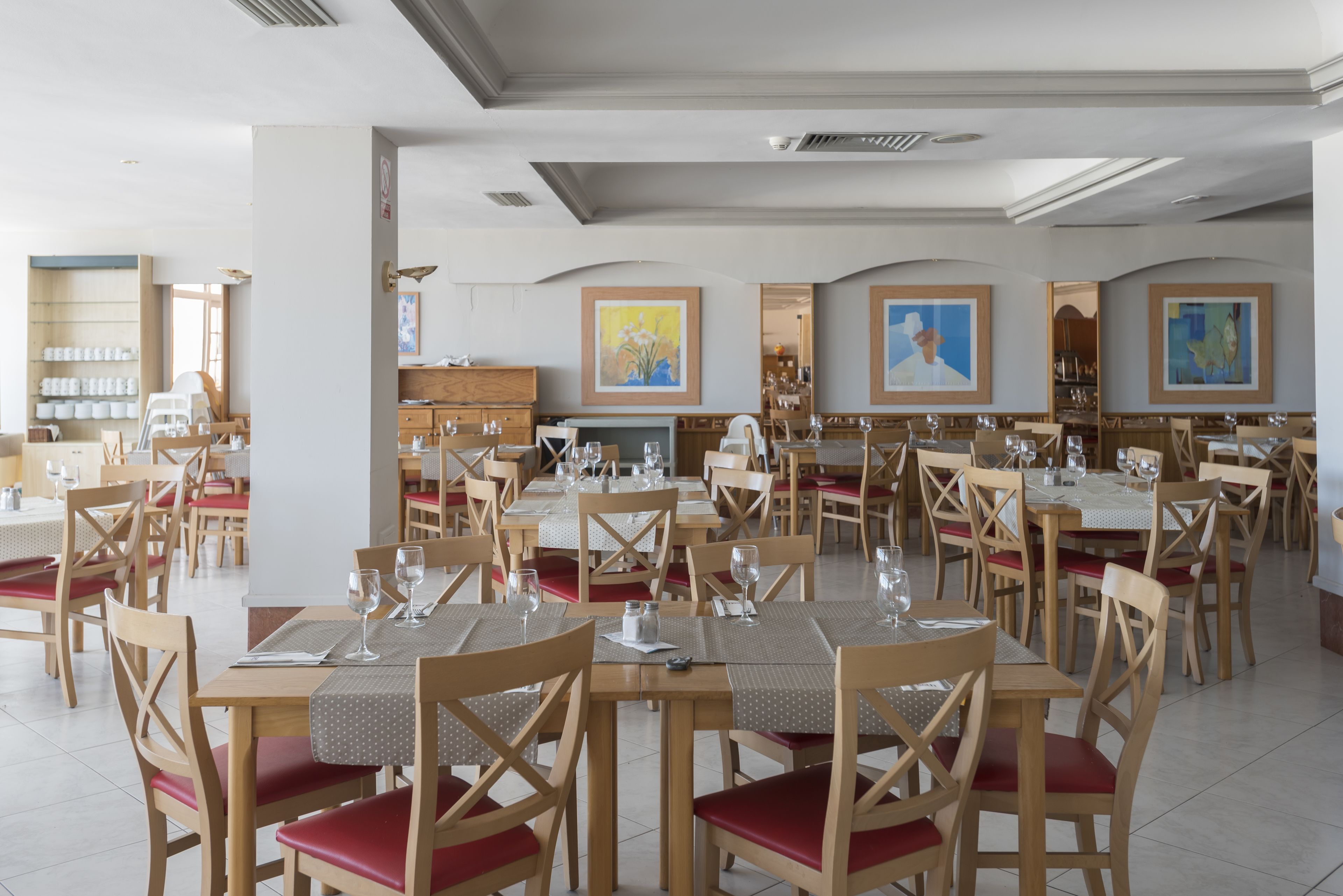 Un restaurant spacieux, doté de nombreuses tables et chaises, chacune étant agrémentée de verres à vin et de menus.