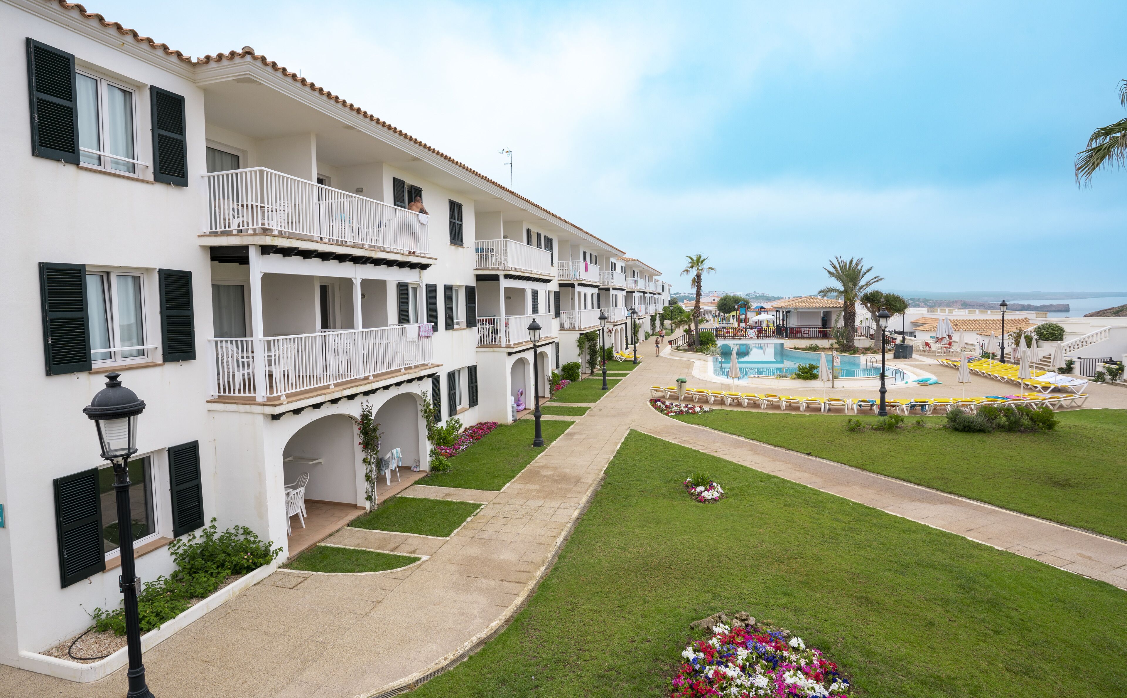 Un resort con edificios de varios pisos, piscina y césped bien cuidado.