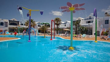 Una piscina con elementi acquatici colorati e lettini da relax.
