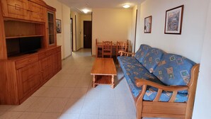 A living room with wooden furniture, a television, a sofa, and a dining table. - Europa Center (Benidorm)