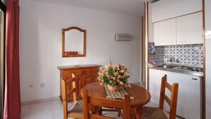 Una cocina compacta con armarios blancos, un salpicadero de azulejos y un horno empotrado.
