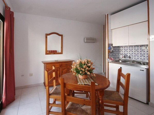 A compact kitchen with white cabinets, a tiled backsplash, and a built-in oven. - Apartamentos Ribera (Benidorm)