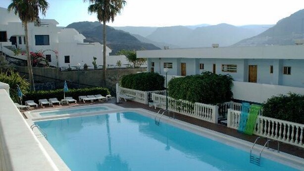 Una piscina amb tanca blanca, gandules i vista a la muntanya.