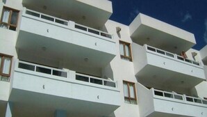Un edifici d'edificis amb balcons, parets exteriors blanques i finestres amb cortines.