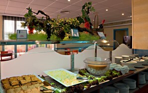 A buffet setup with various food items, a decorative plant, and a coffee station. - Tropic Relax (Finestrat)