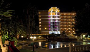 A multi-story hotel with a central atrium, a swimming pool, and palm trees. - Tropic Relax (Finestrat)