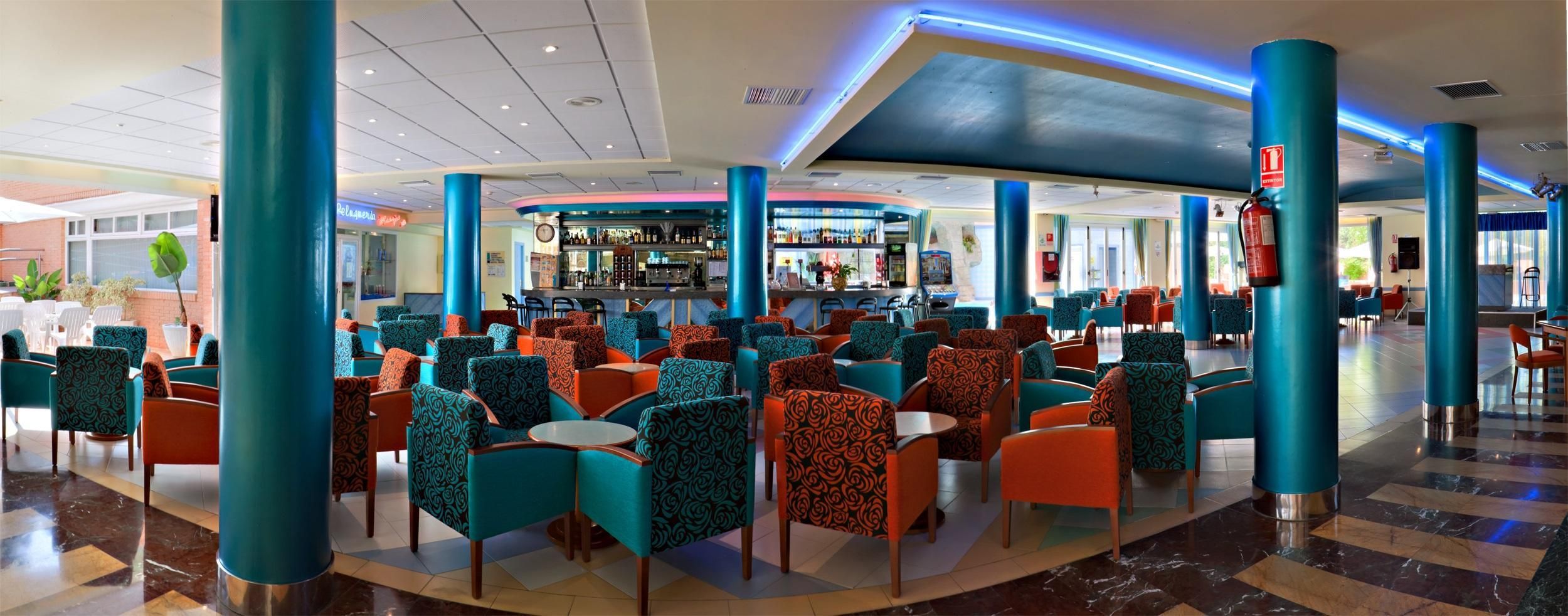 A spacious indoor area with multiple seating arrangements, a bar area, and a fire extinguisher mounted on a pillar.