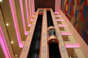 A multi-level interior with a central staircase, illuminated by pink lighting, and a colorful geometric wall pattern. - Tropic Relax (Finestrat)