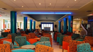 Amplio espacio interior con diversas opciones de asientos, incluyendo sofás y sillones, y un escenario con fondo decorativo.