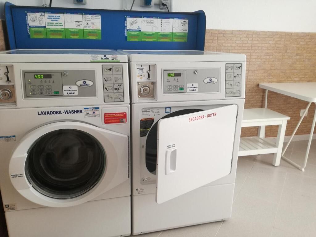 A laundry area with a front-loading washer and dryer, control panels, and a small table.