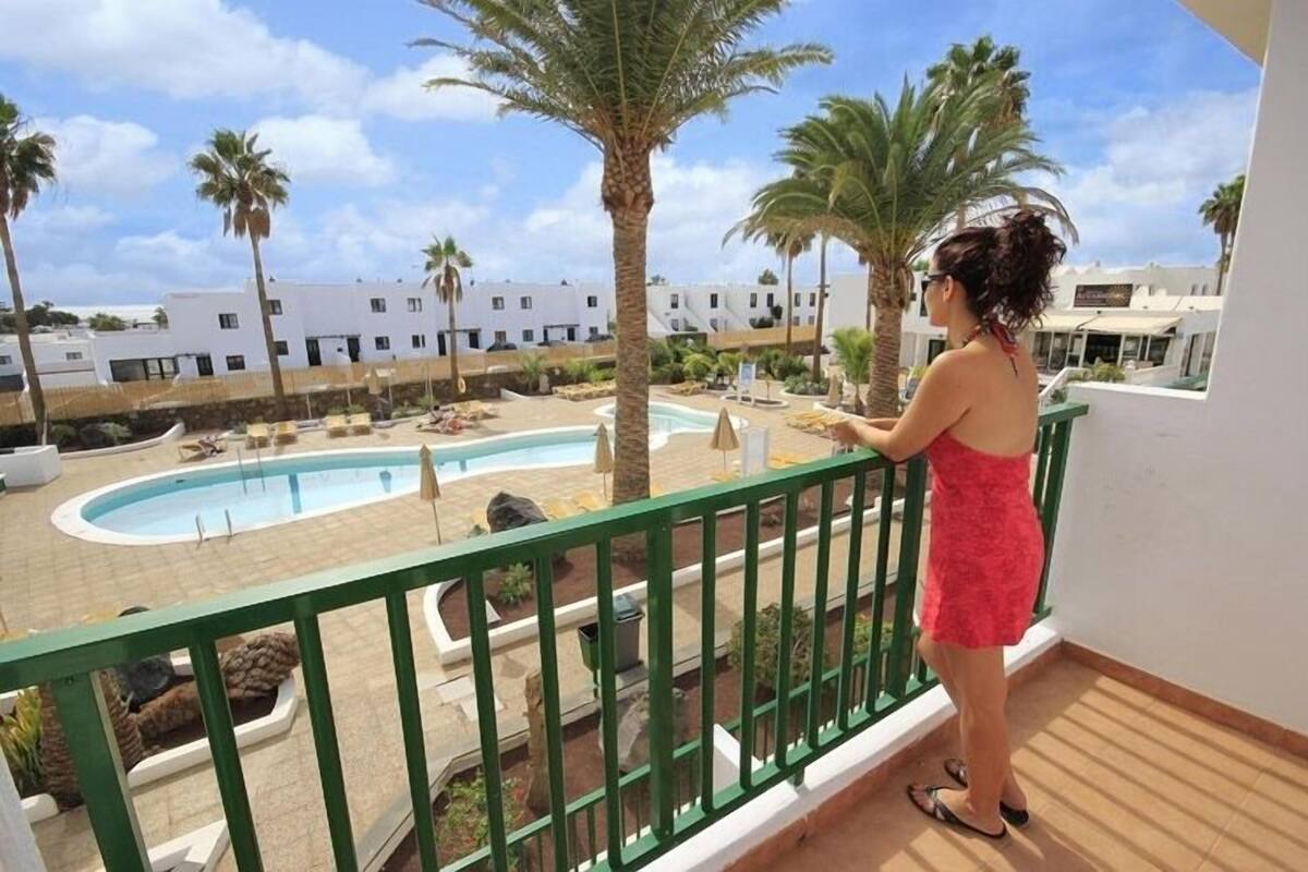 Ein Balkon mit Blick auf einen Swimmingpool und Palmen.