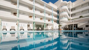 Un hôtel moderne doté d’un espace piscine à plusieurs niveaux, de nombreux balcons et de chaises longues.