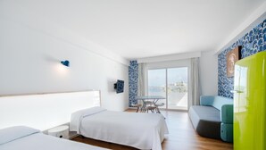 Une chambre d’hôtel avec deux lits, une table à manger, un canapé et une vue sur la ville.