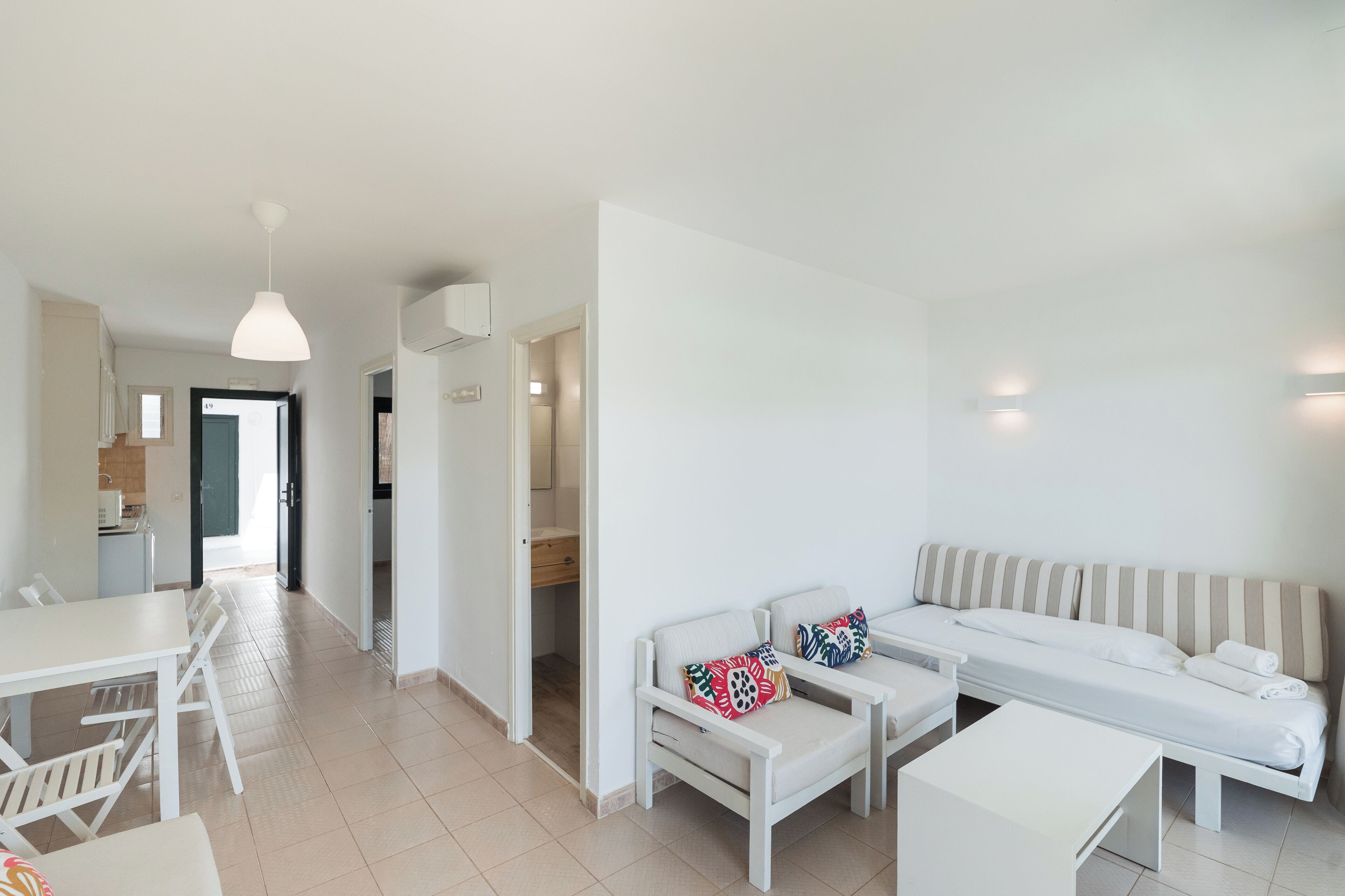 Un salon moderne et minimaliste, avec un canapé, une petite table et un coin repas.
