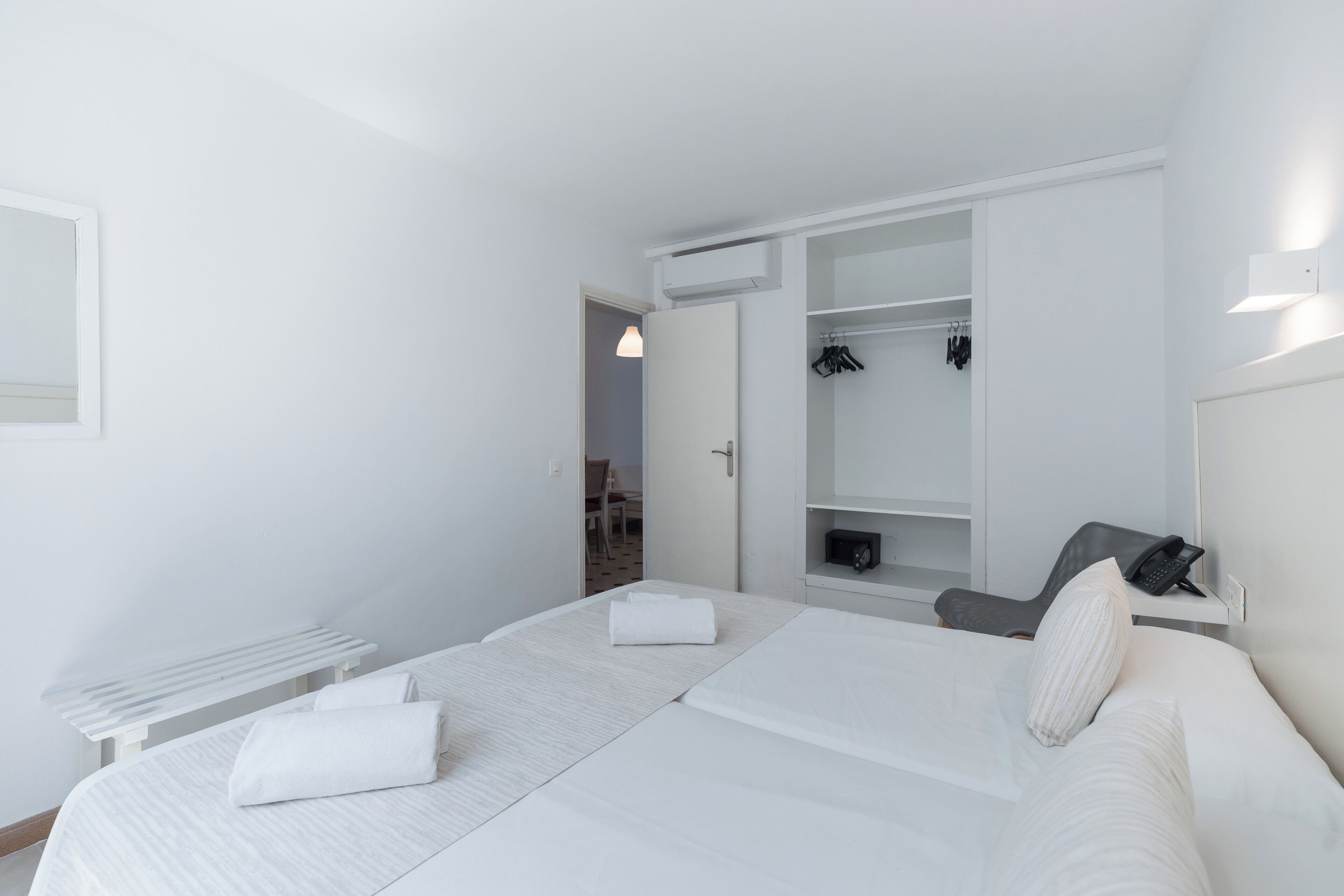 A modern hotel room with a large bed, a desk, and a walk-in closet.