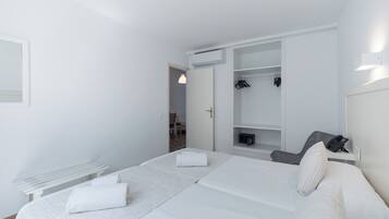 A modern hotel room with a large bed, a desk, and a walk-in closet.