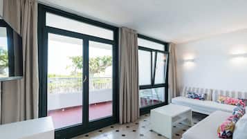 Una sala de estar moderna con un sofá, una mesa de centro y ventanas grandes con cortinas.