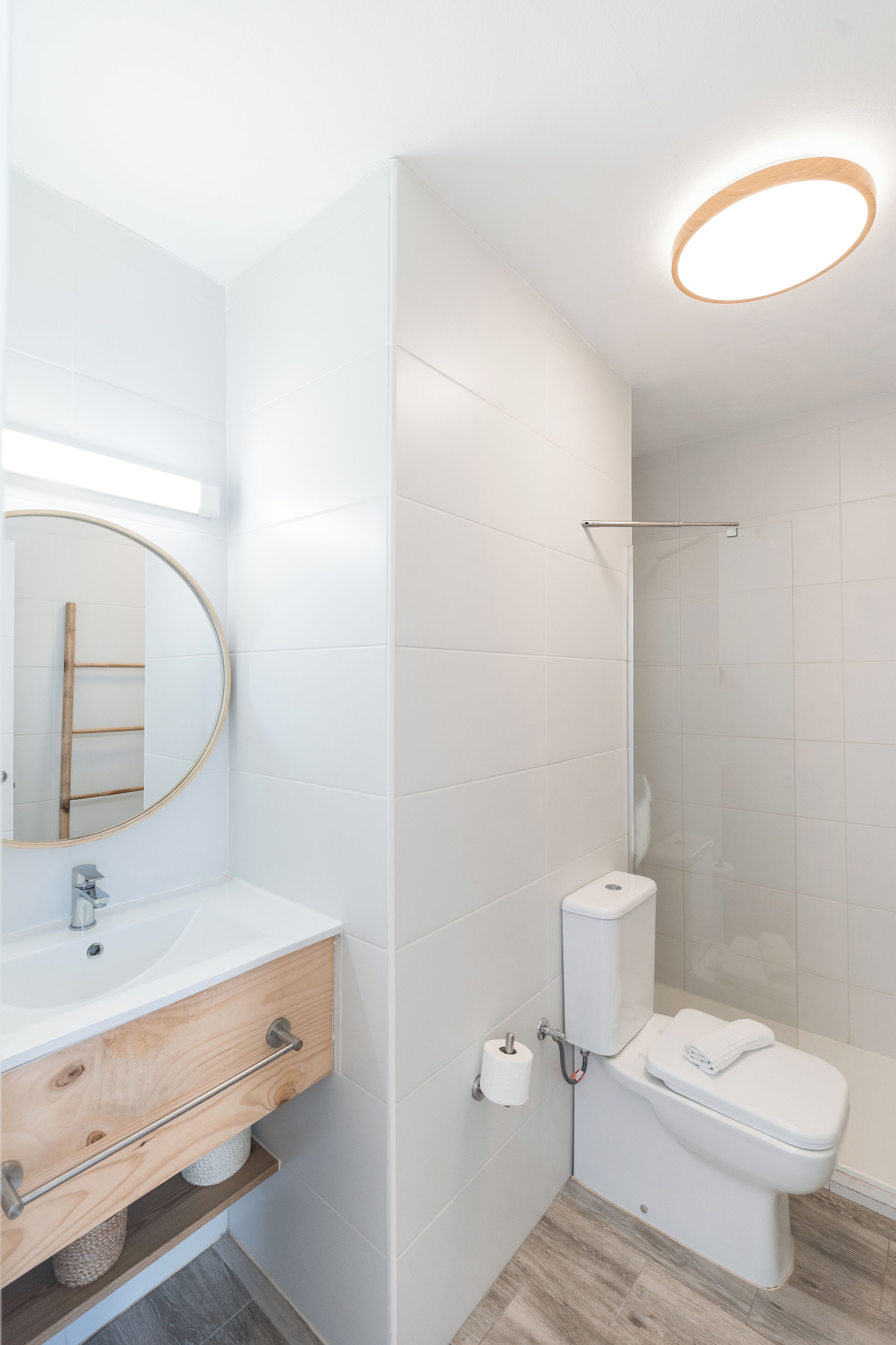 Un baño moderno con lavamanos, espejo y retrete blancos.