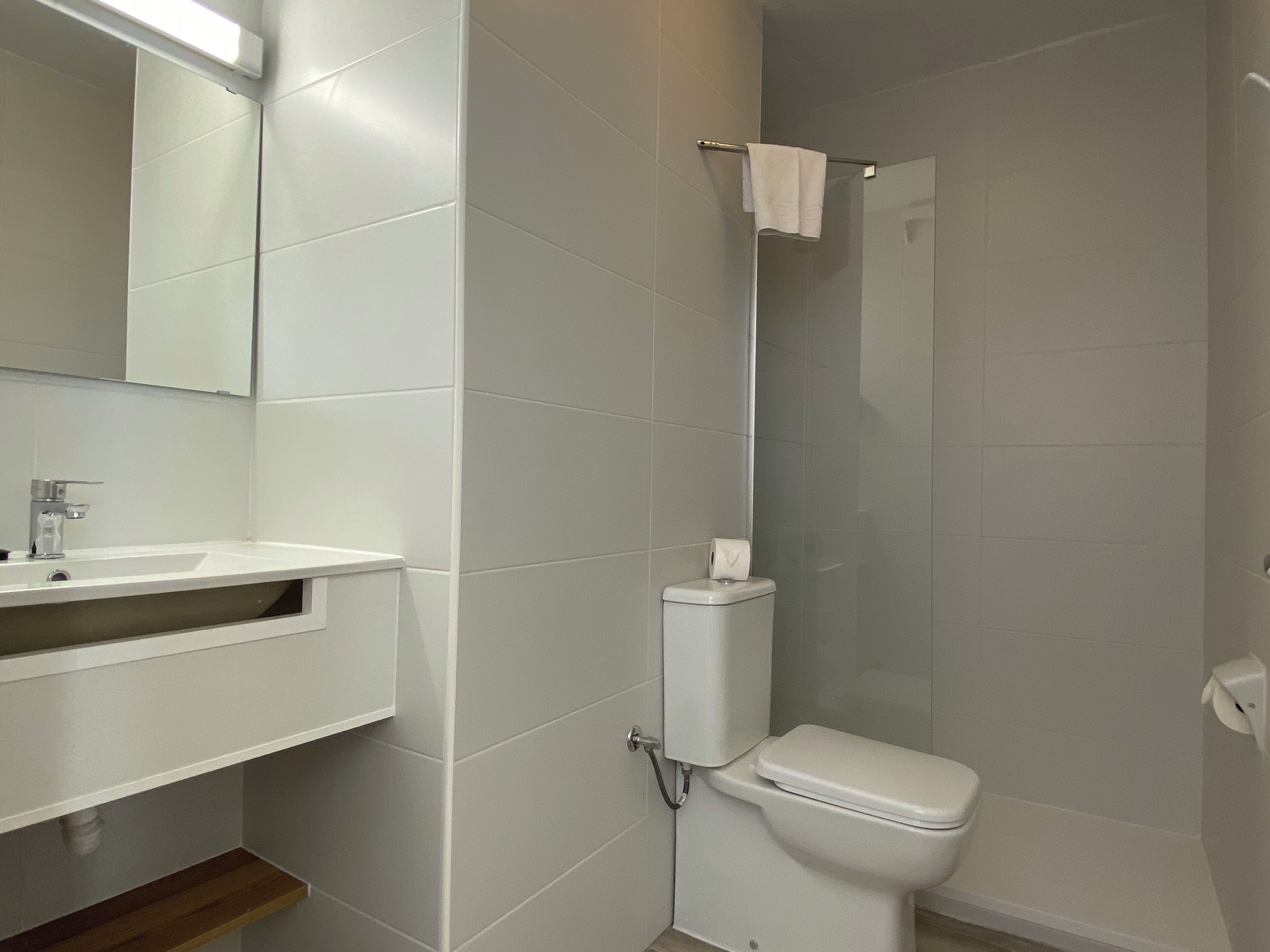A bathroom with a white sink, mirror, toilet, and shower.