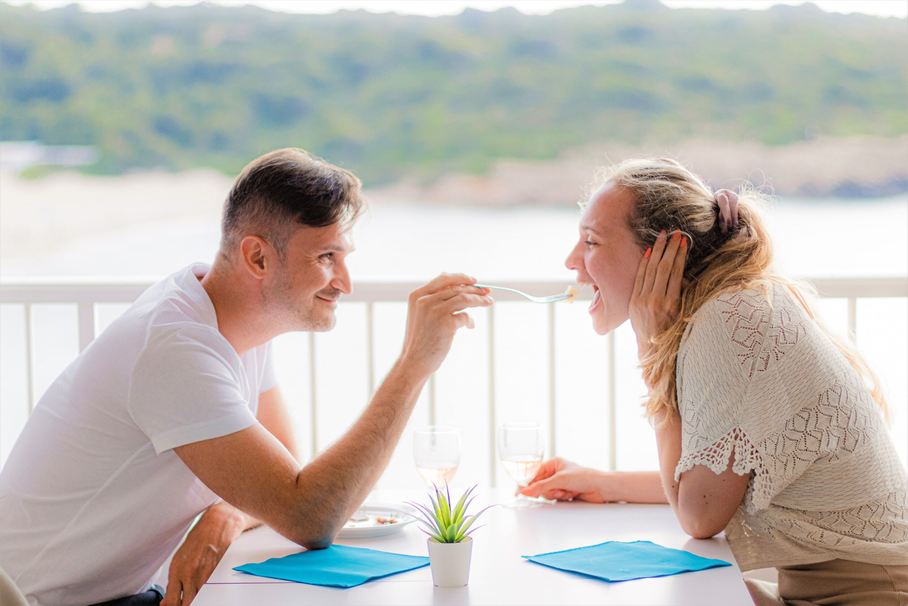 Una pareja cenando en una mesa con vista al agua.