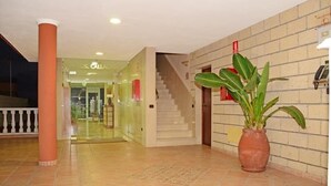 A hotel lobby with a glass entrance, a staircase, and a potted plant. - Callaomar (Adeje)