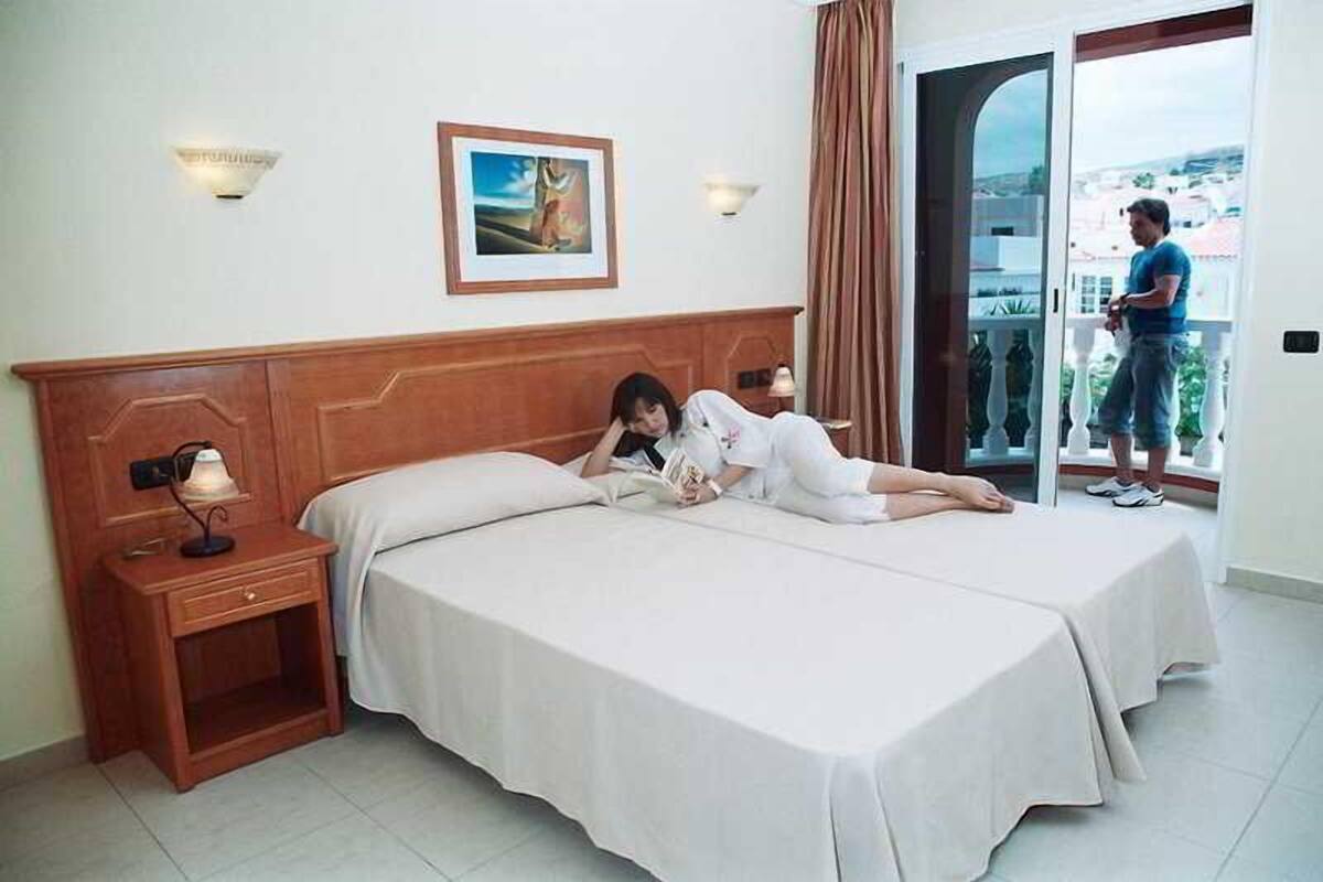 Ein Hotelzimmer mit zwei Betten, einem Nachttisch, einer Lampe und einem Bild an der Wand.
