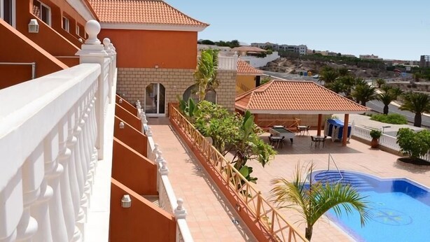 A hotel with a swimming pool, outdoor seating, and a view of the surrounding area. - Callaomar (Adeje)