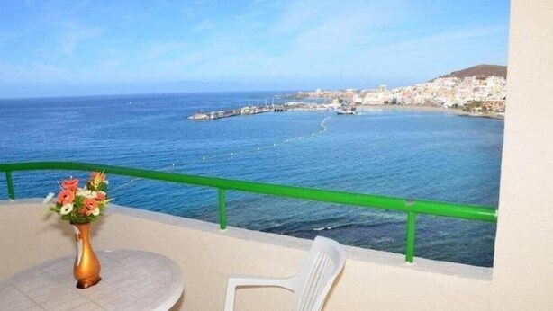 A balcony with a view of the sea and a distant town. - Apartamentos Costamar (Arona)